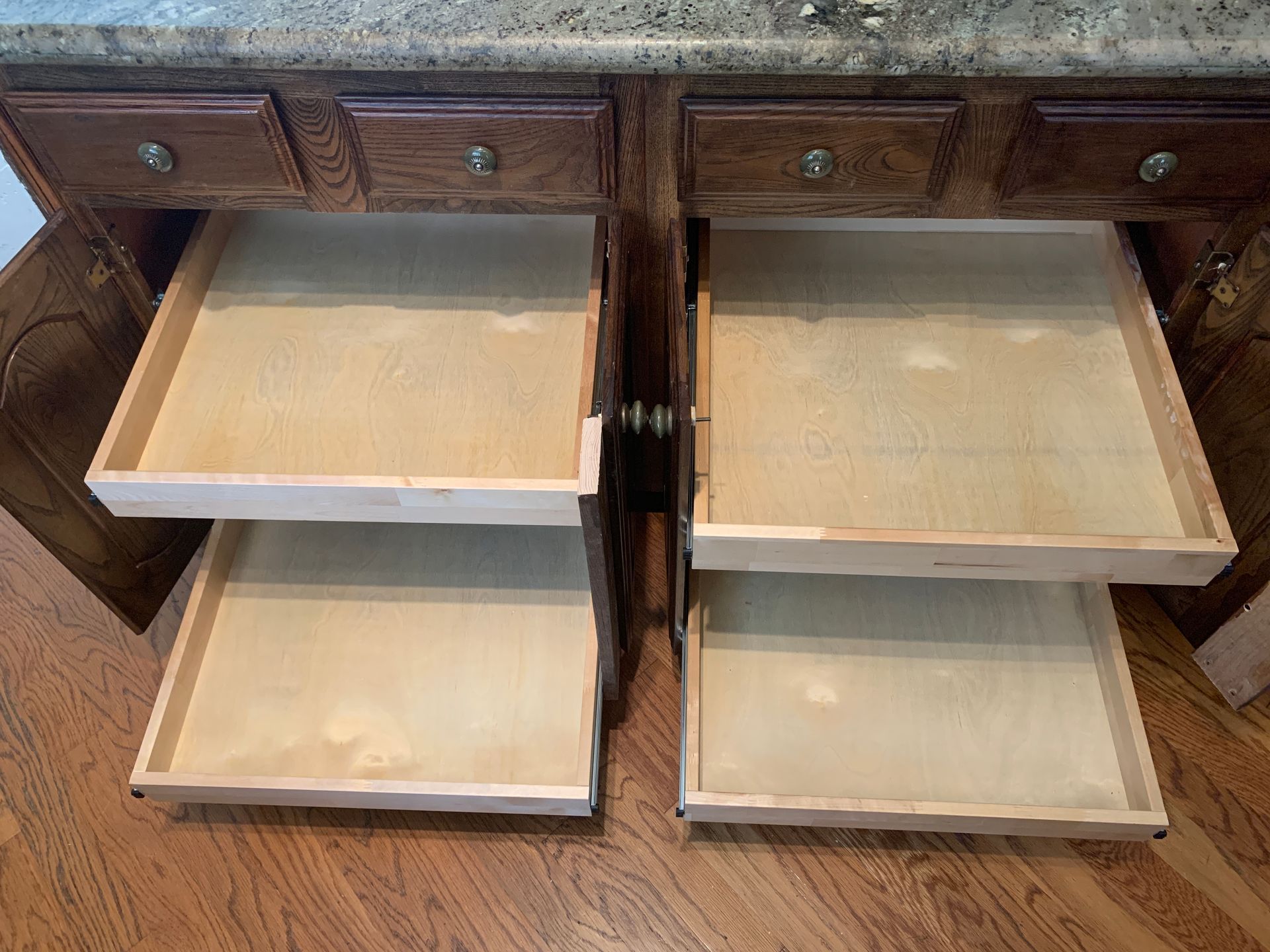 Open kitchen cabinet with pull-out drawers, showing wooden interior.