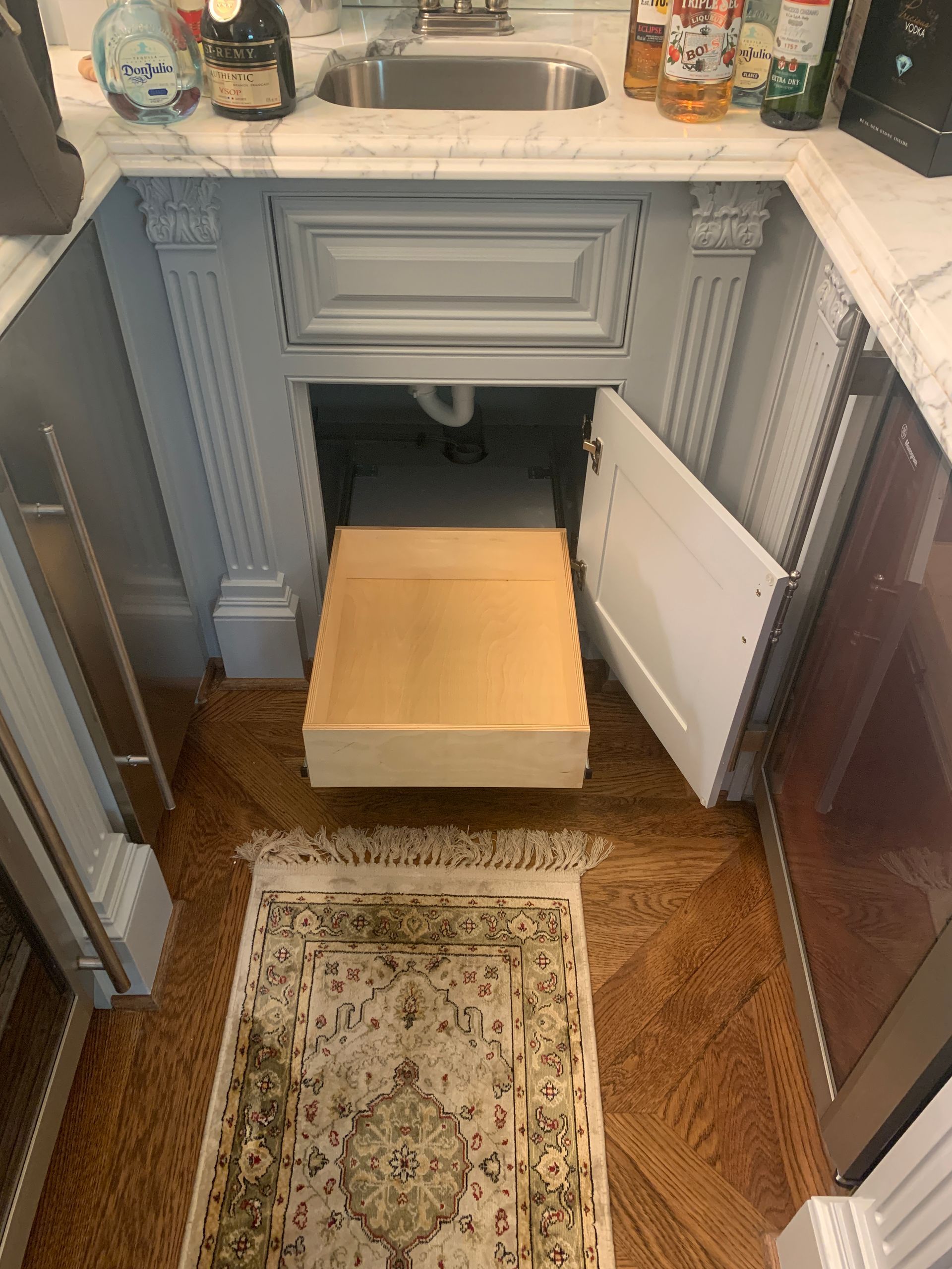 Kitchen sink area with a pull-out step, accessible storage, and marble countertops.