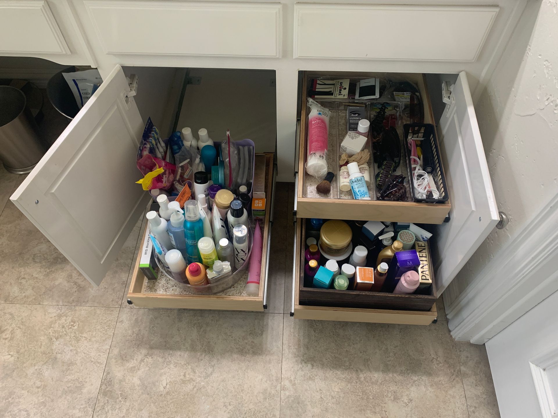 Open bathroom vanity cabinets with pull-out drawers full of toiletries.