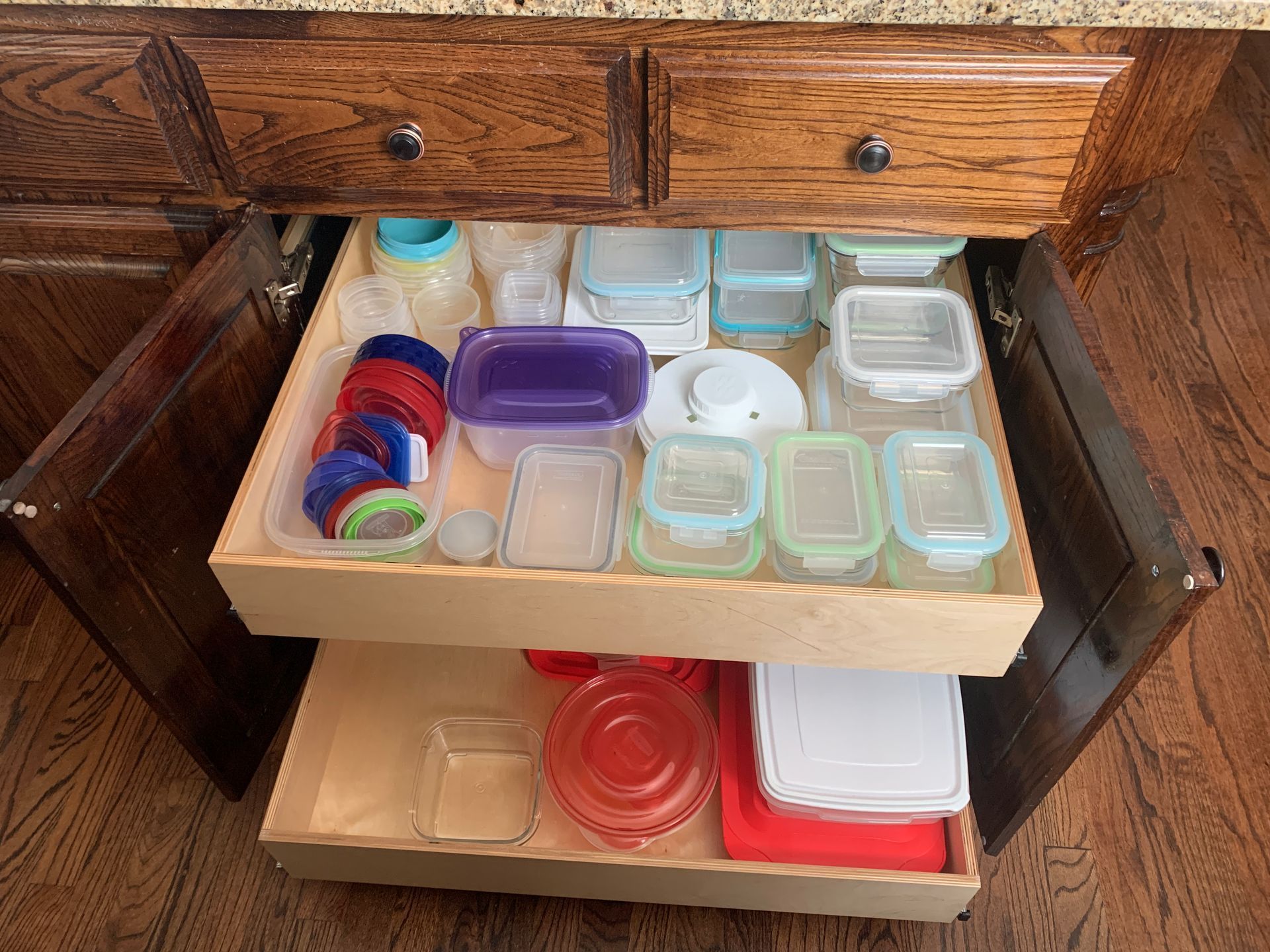 Kitchen cabinet with pull-out drawers holding various food storage containers.