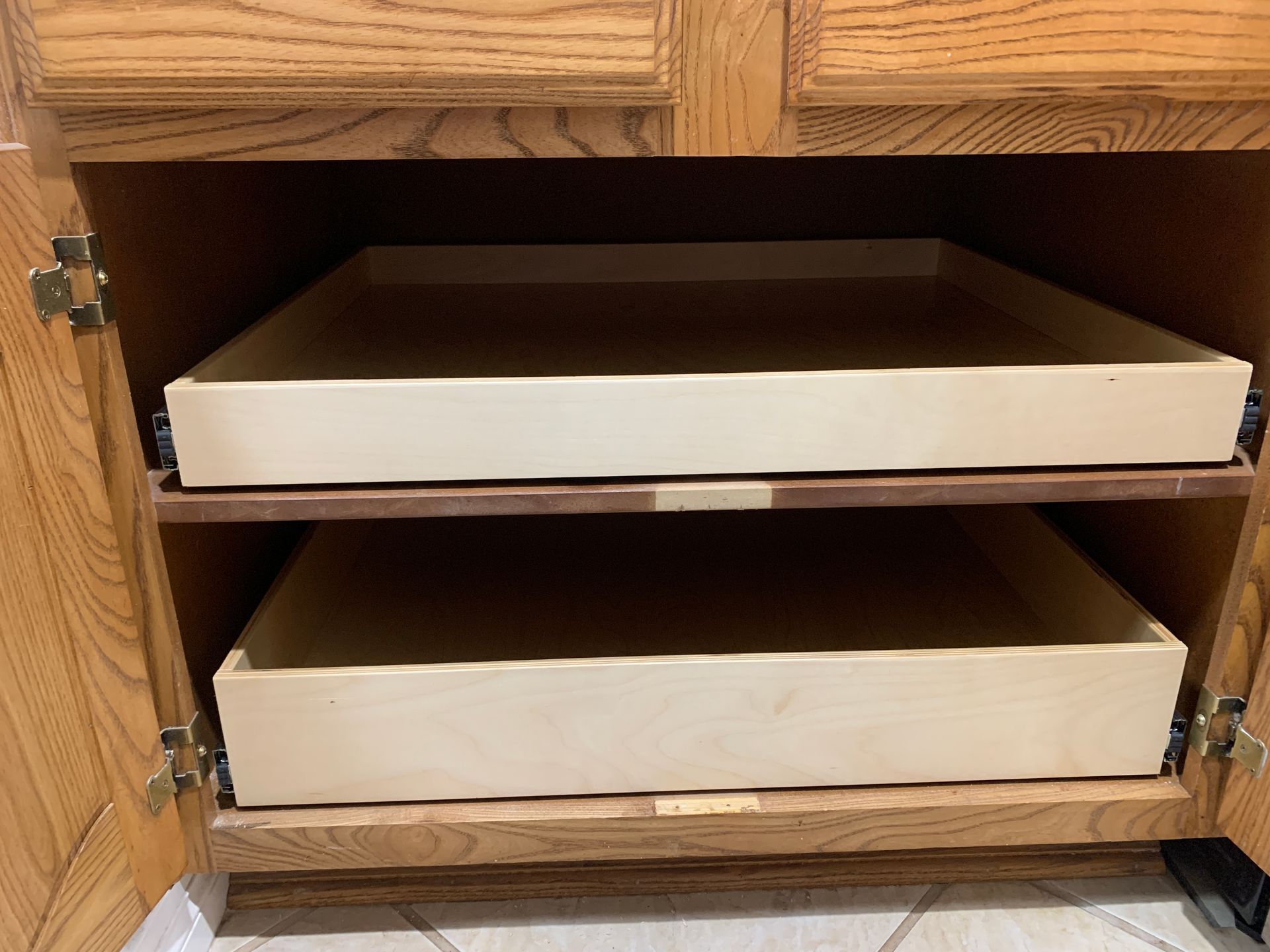 Cabinet with two pull-out trays, light wood color, inside an oak-colored cabinet.
