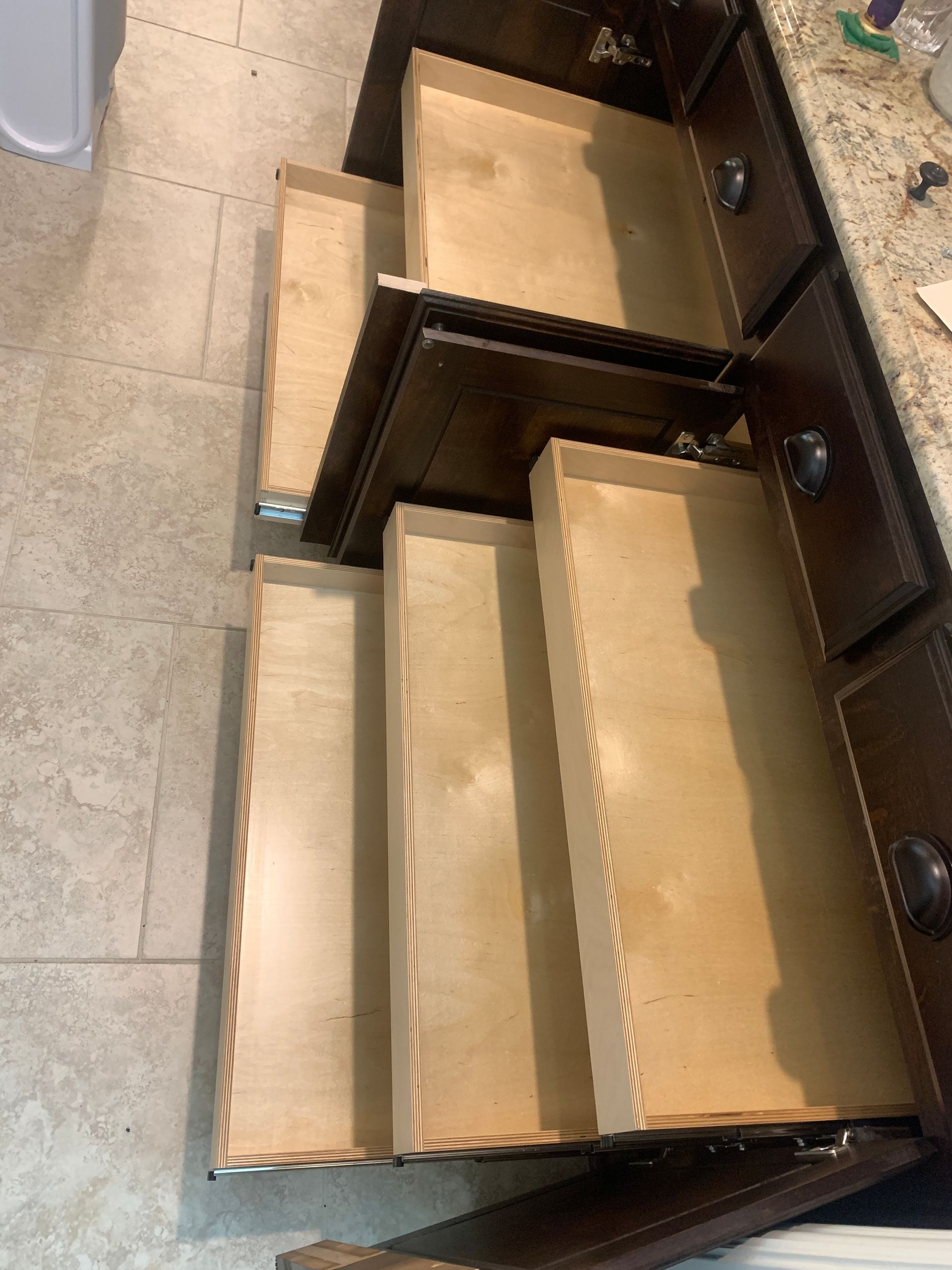 Kitchen cabinet with multiple open drawers, showcasing their interior and placement.