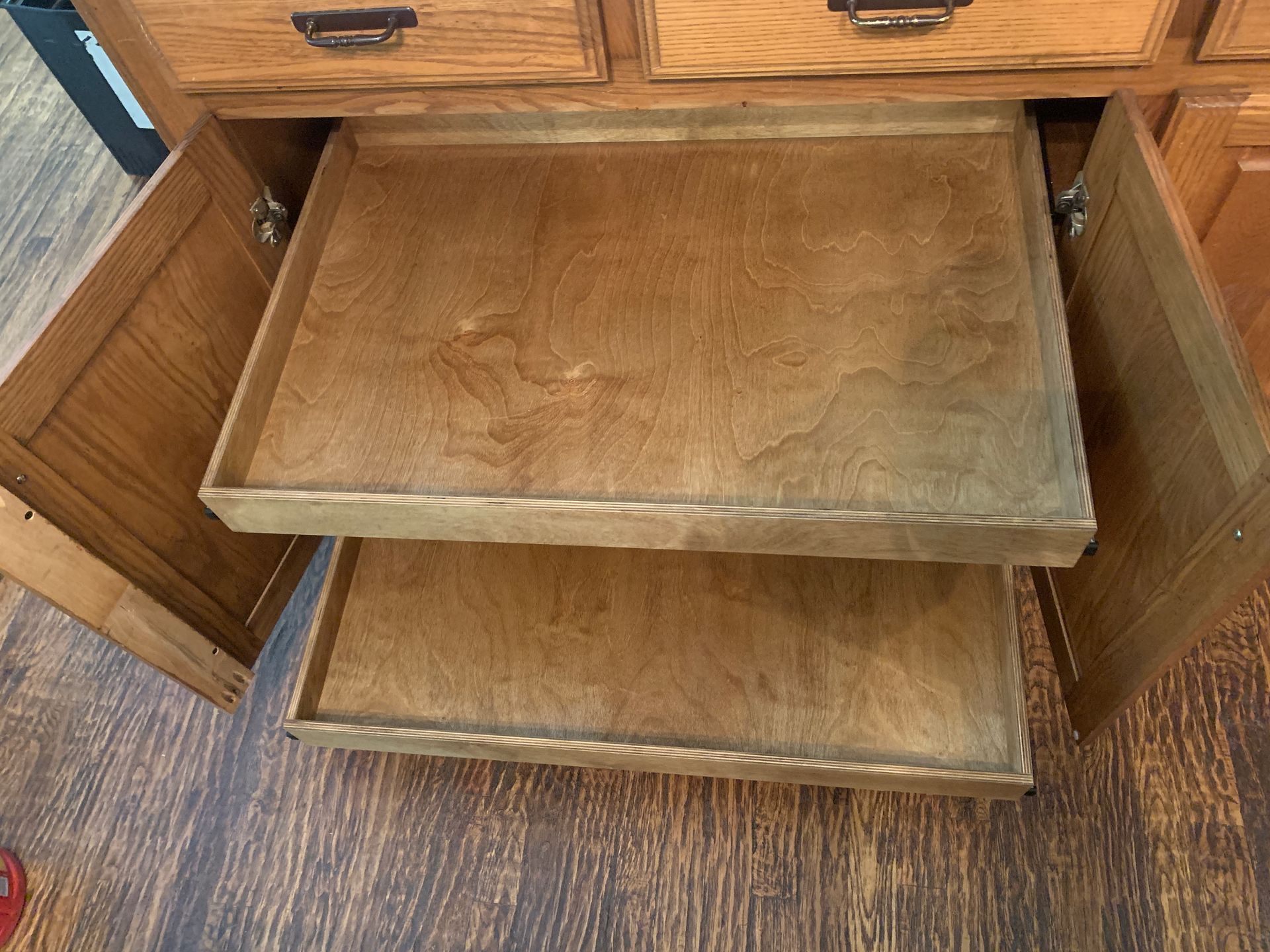 Wooden cabinet with two pull-out shelves inside. Cabinet doors are open.