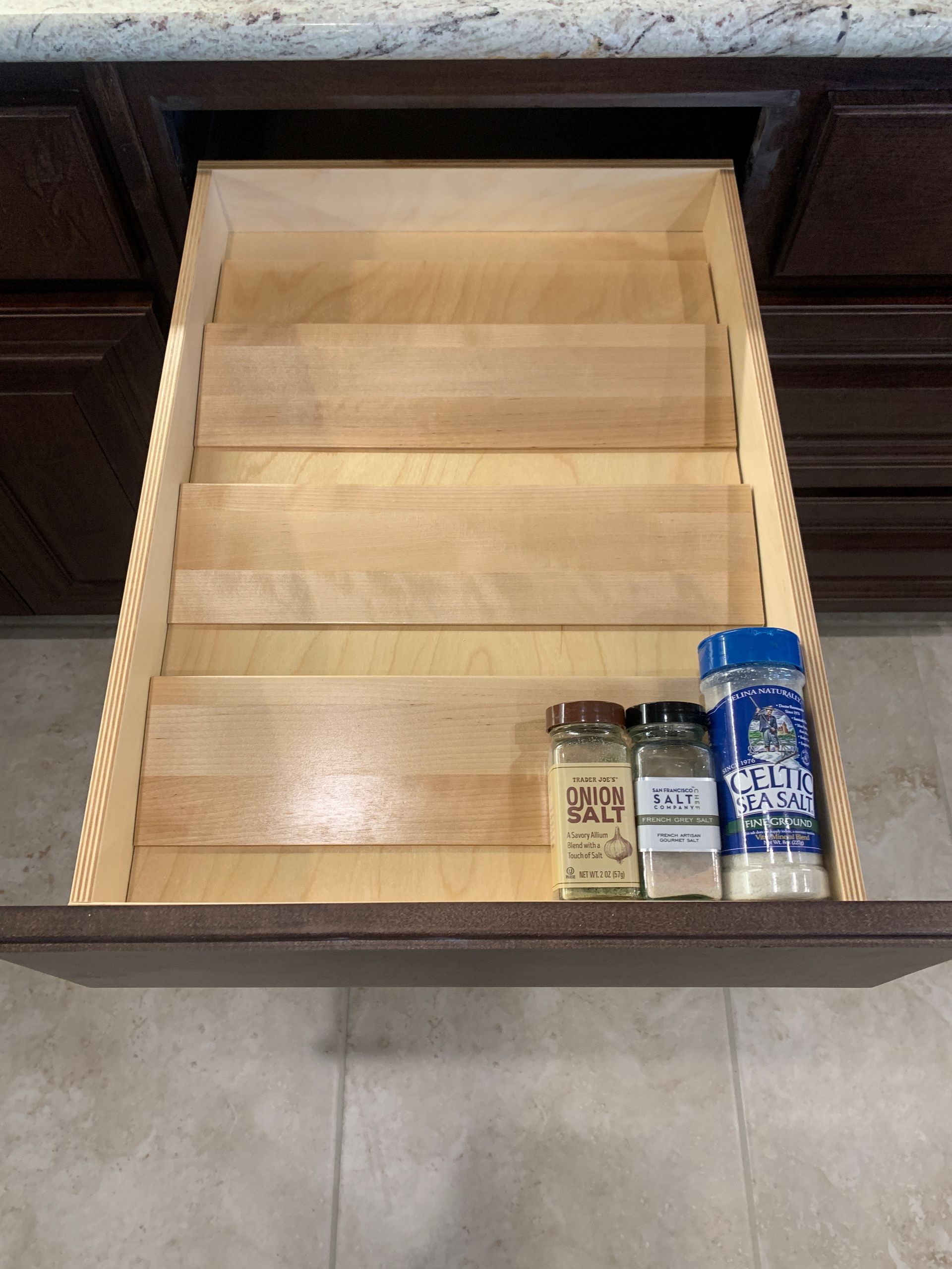 Open kitchen drawer with spice rack and three spice containers.