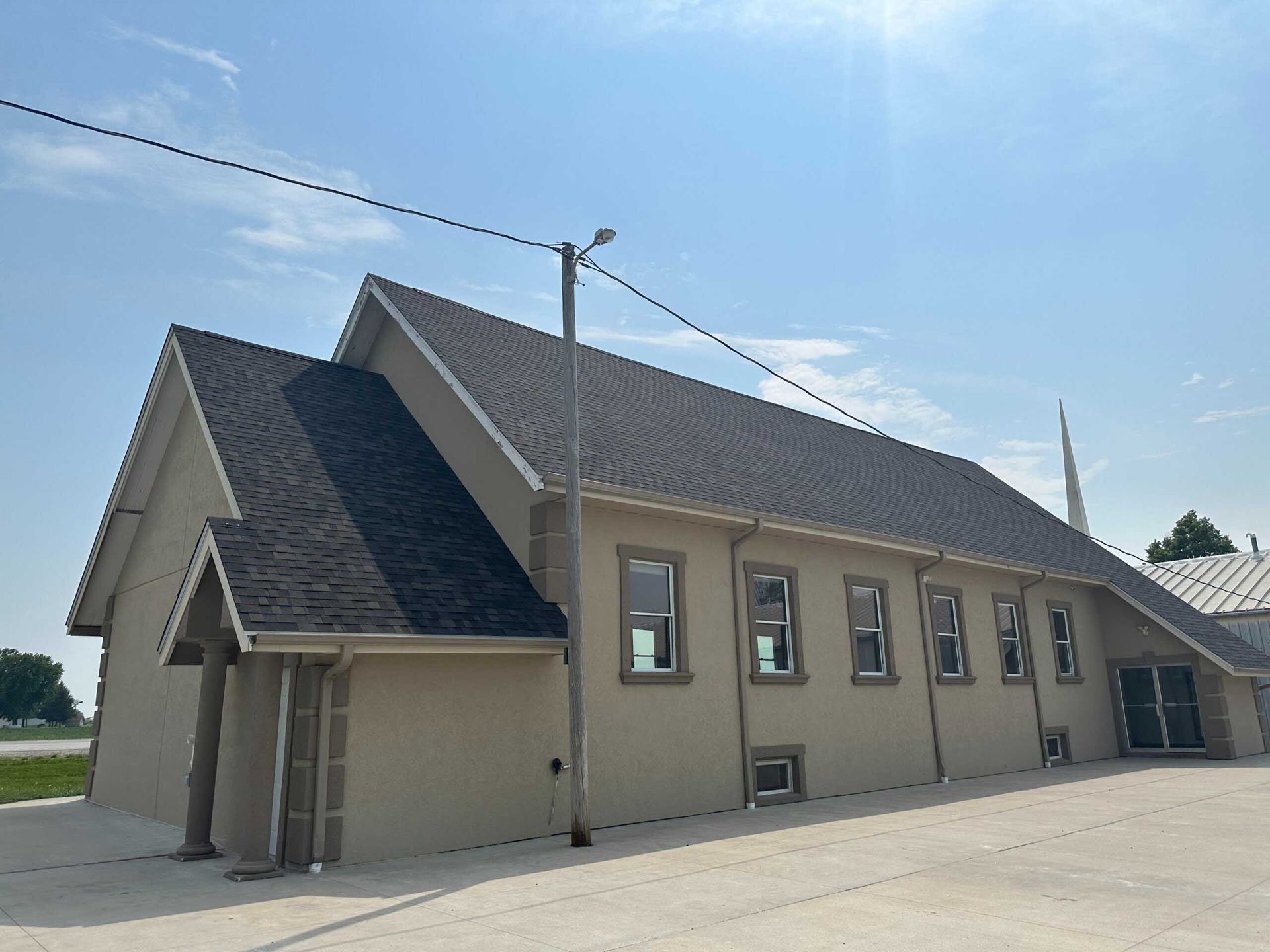 Tan beige building with dark roof and several windows under a clear blue sky
