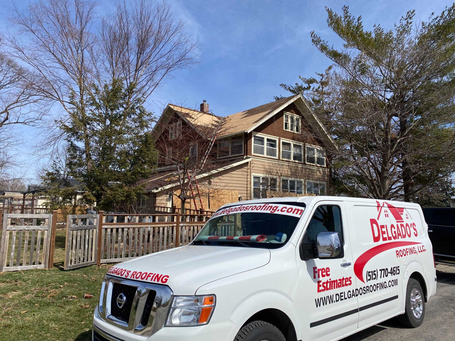 White van with red business lettering parked in front of a wooden house and fenced yard