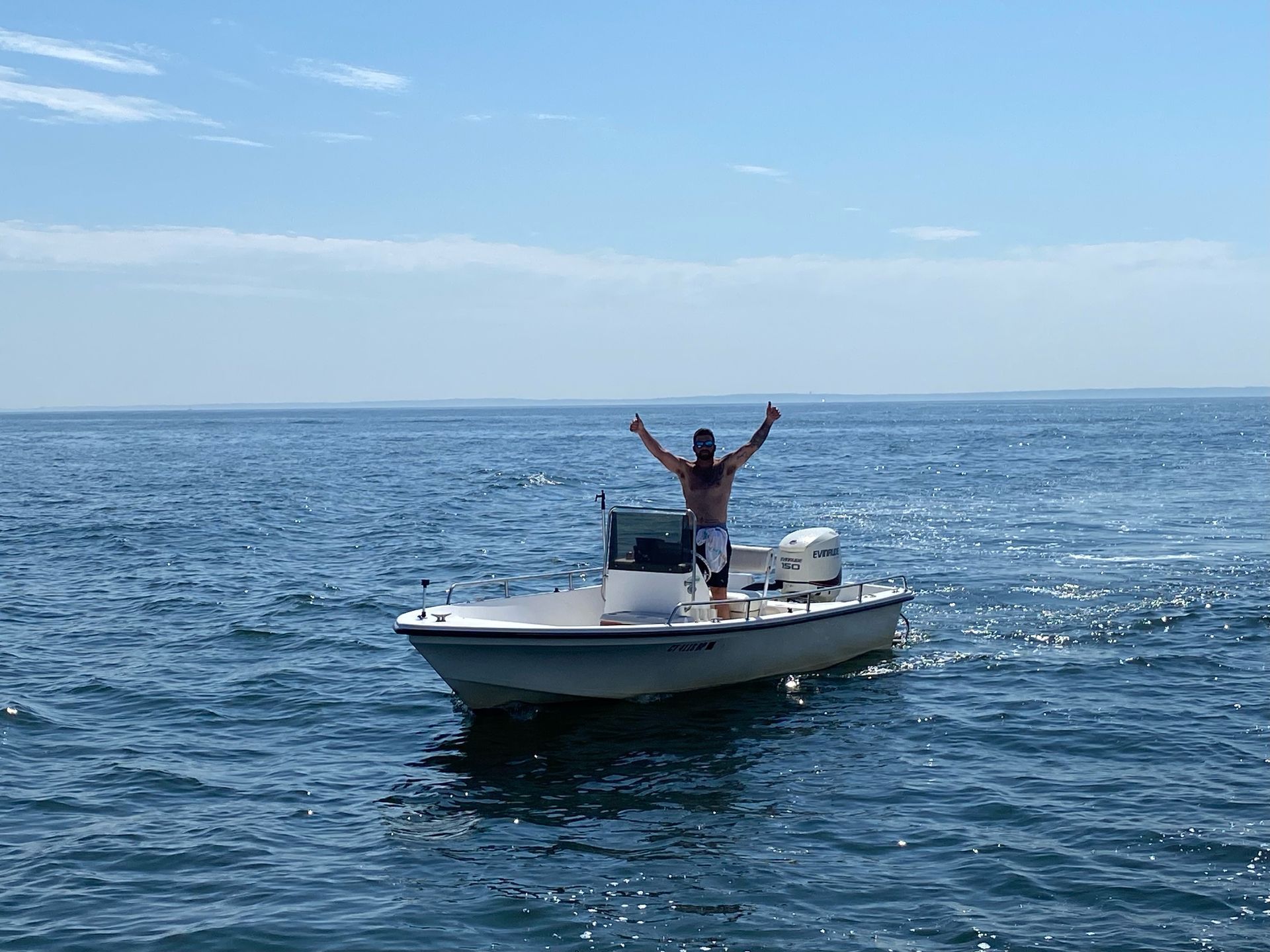 A man is standing on a boat in the ocean with his arms in the air