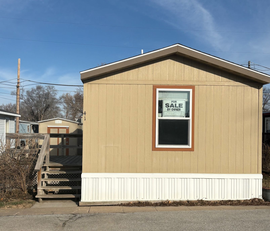 Yellow mobile home with for sale sign. 
