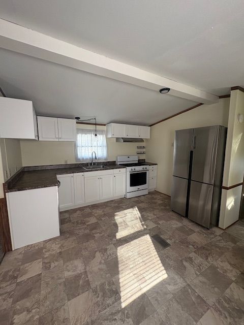 Kitchen with white cabinets, stainless steel refrigerator, and linoleum floors.
