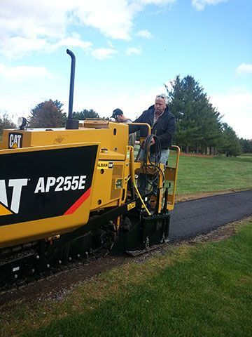 A man is driving a cat ap255e asphalt paving machine