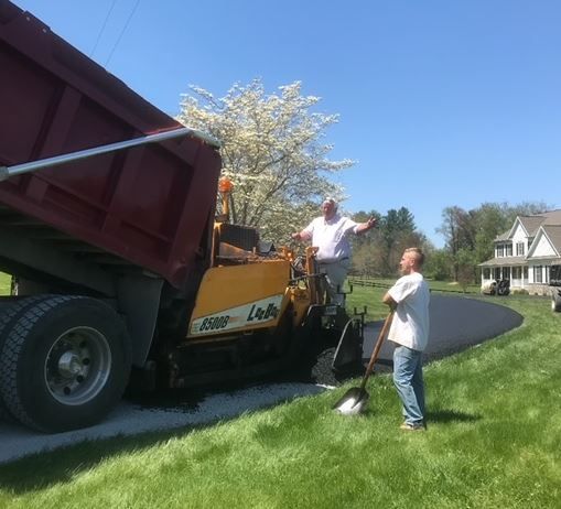 Two men are standing in front of a dump truck.