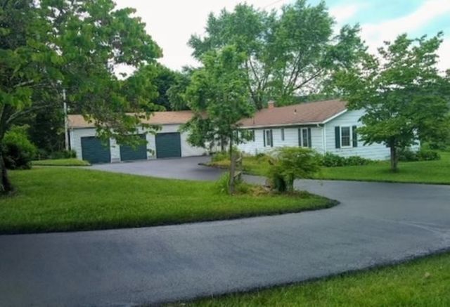 A driveway leading to a white house with two garages