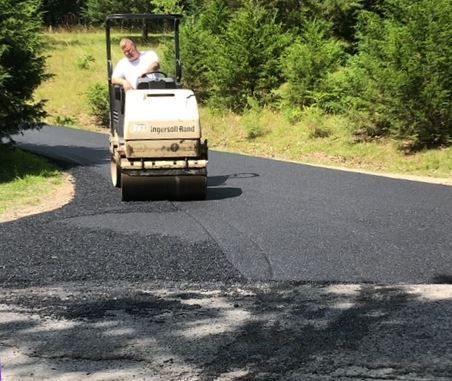 A man is driving a roller on a road.