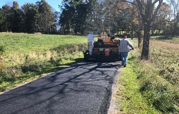 A man is walking down a road next to a truck.