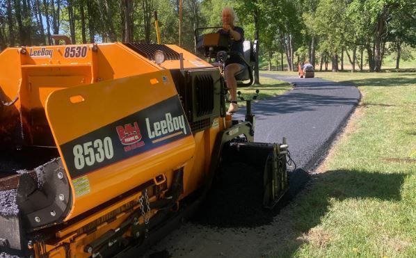 A yellow asphalt paving machine is sitting on the side of a road.