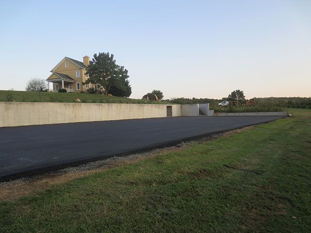 A house is sitting on top of a grassy hill next to a road.