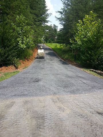 A truck is driving down a road surrounded by trees.