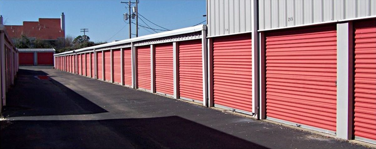 Row of red storage unit doors along a paved alley
