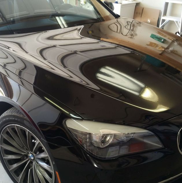 Black BMW sedan with a glossy reflective hood in a garage
