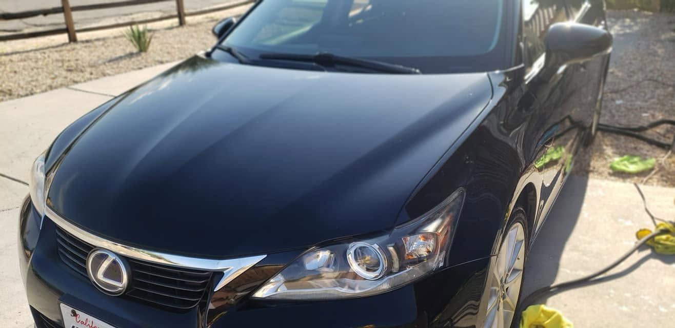 Black Lexus sedan parked outdoors in daylight, front view with chrome grille and headlights visible