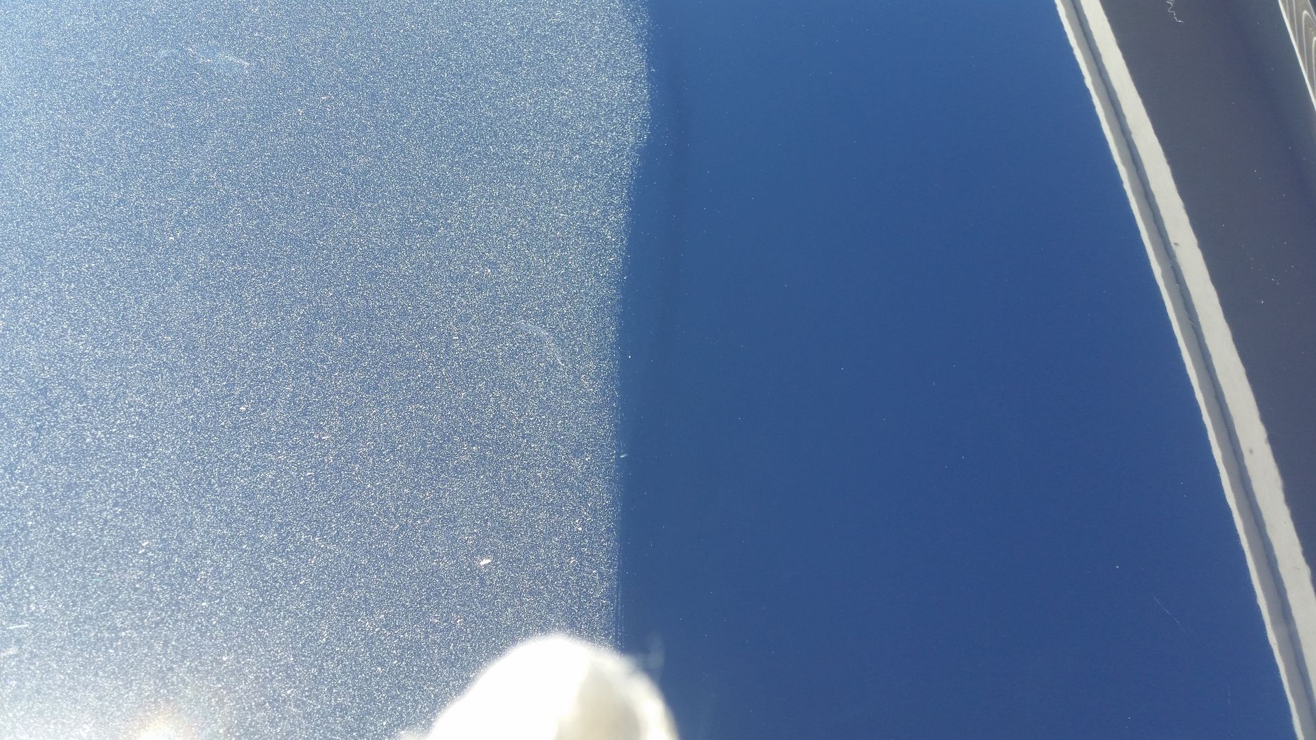Close-up of a blue car hood showing dirt on the left side and a cleaned surface on the right side.