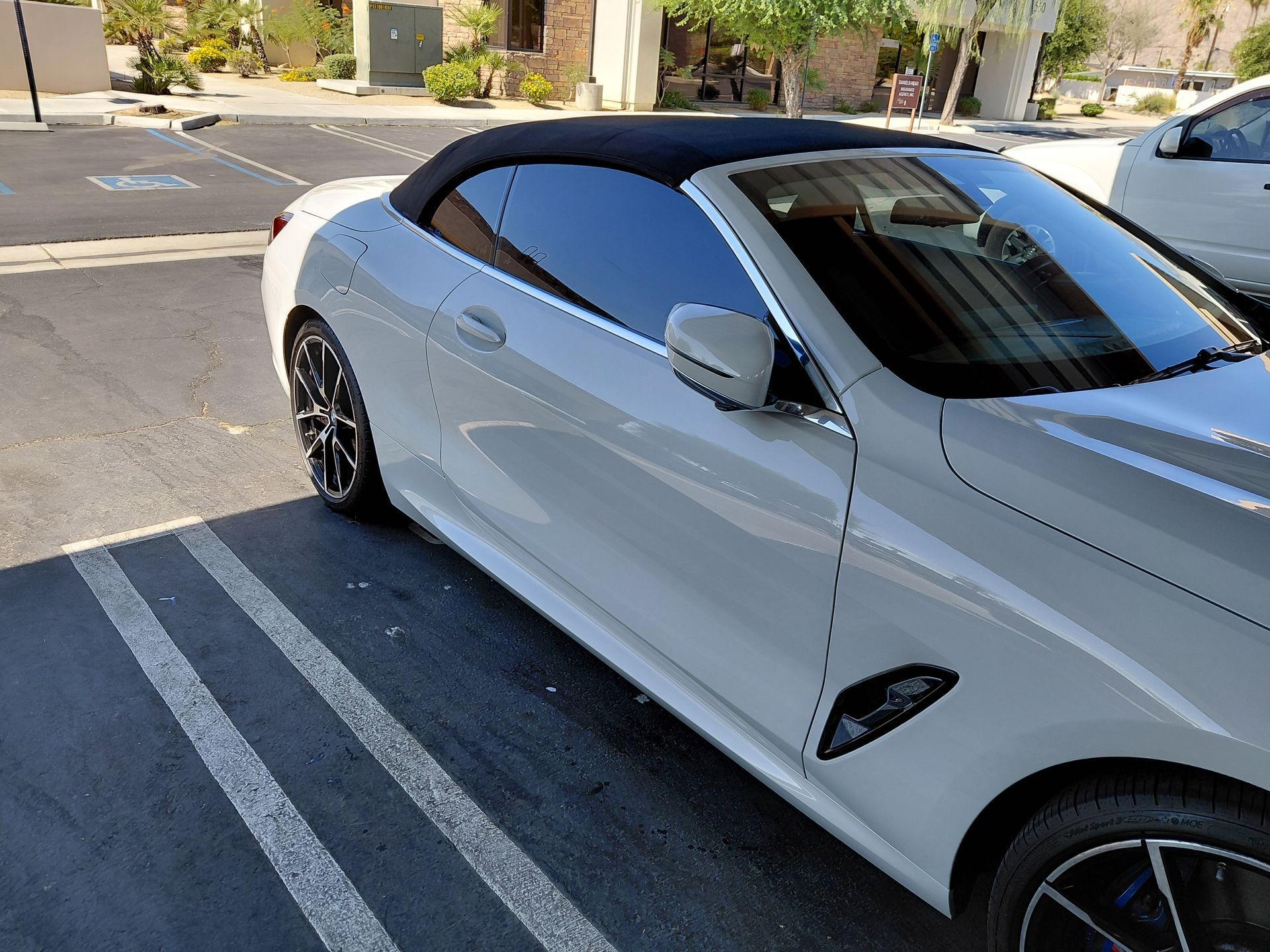 White sports car parked in a striped parking space on a sunny street