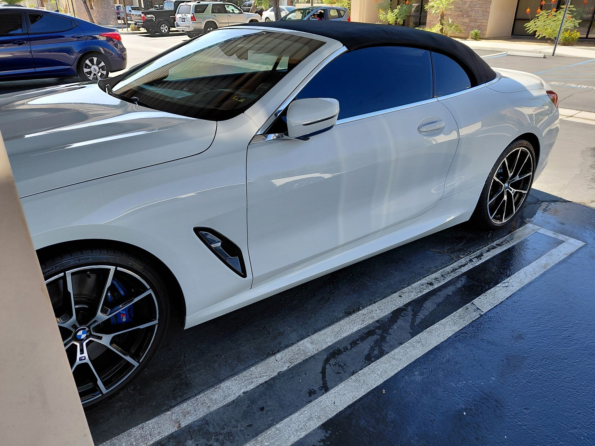 White convertible sports car parked in a lot with dark tinted windows and black rims