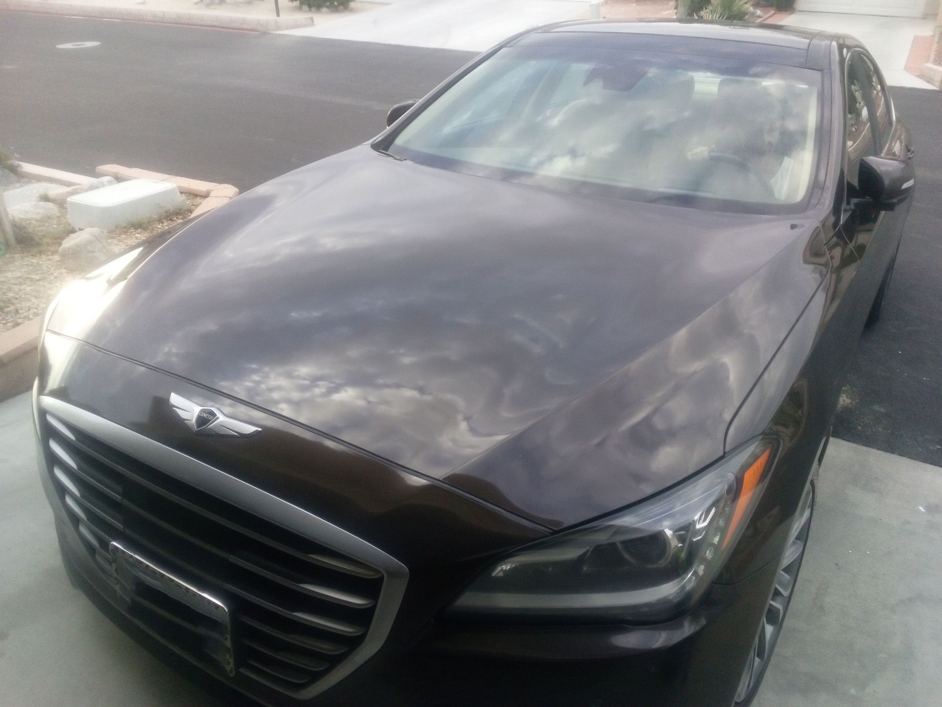 Black sedan parked outdoors, front view with chrome grille and headlights, slightly angled in a parking lot.