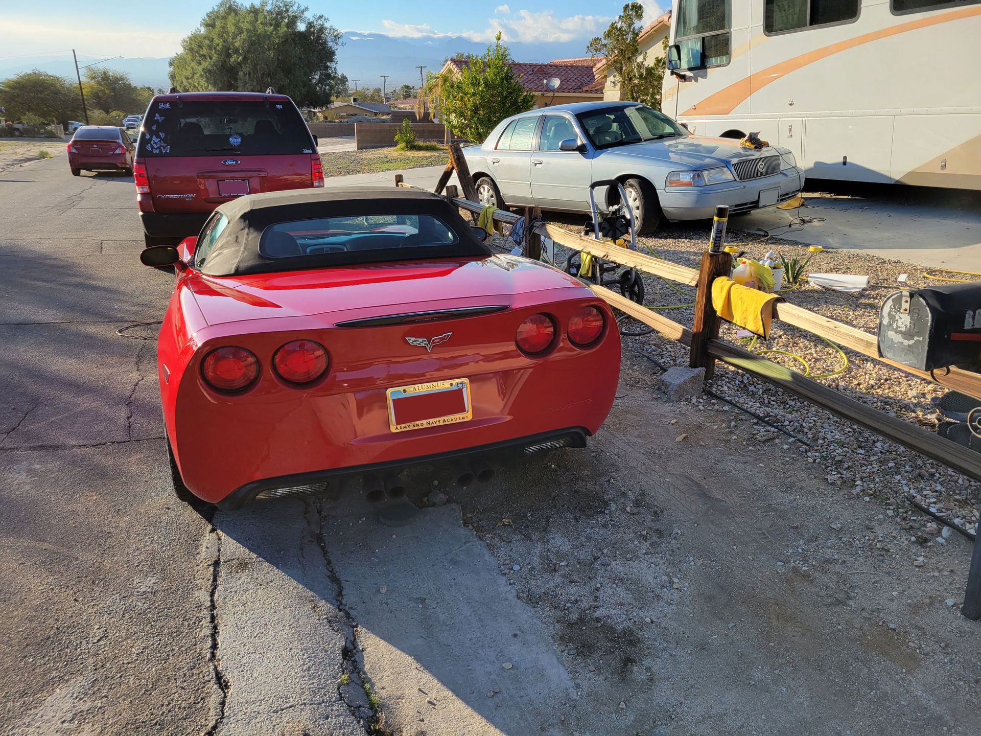 Red convertible and two other cars after a crash on a road beside a guardrail and RV.
