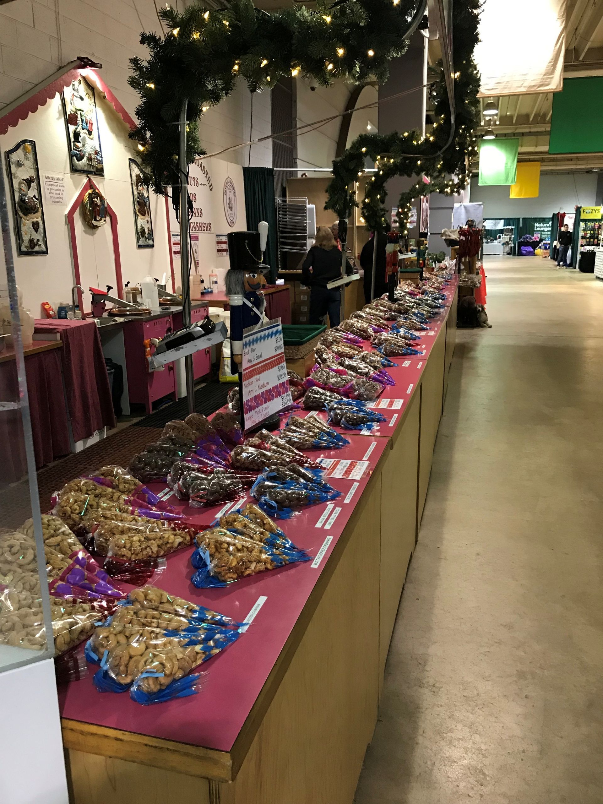 Holiday market stall with tables of colorful baked goods and candy under festive lights