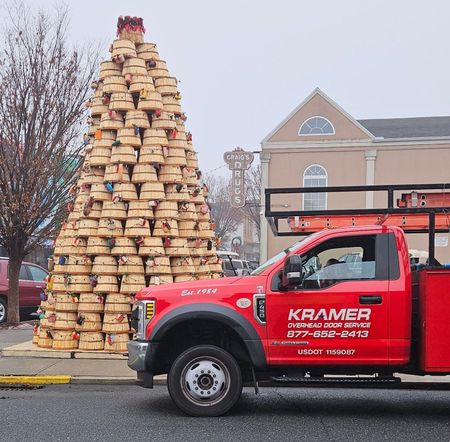 A red kramer truck is parked in front of a stacked christmas tree