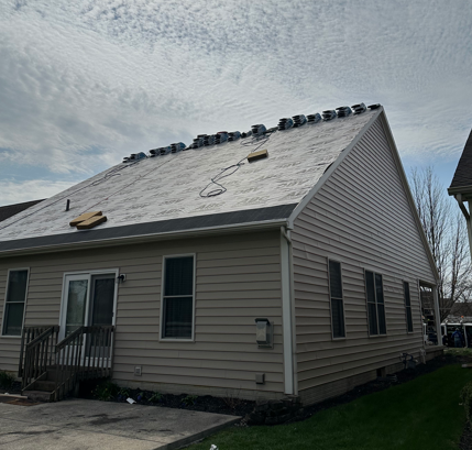 House with new roof shingles being installed on a cloudy day