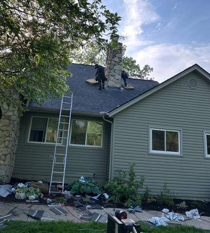 Workers repairing a house roof with ladders, shingles, and debris in the yard