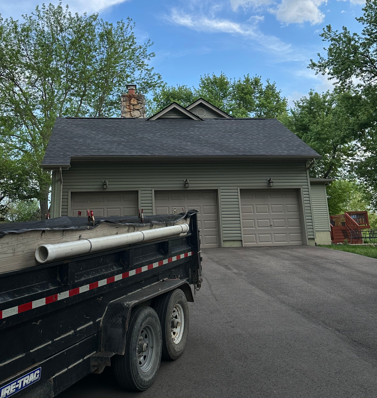 Driveway and attached garage of a house, with a black utility trailer in the foreground.