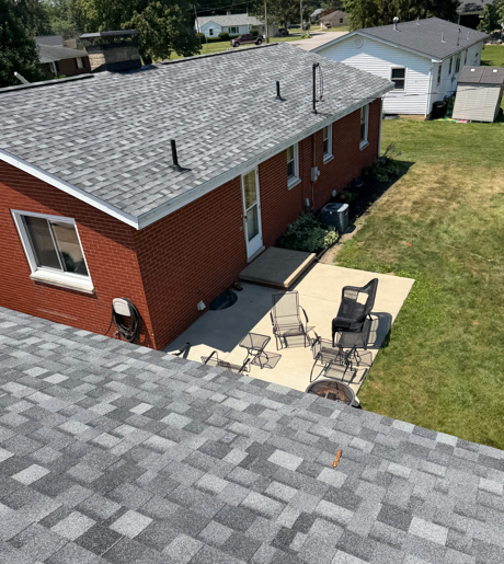Aerial view of a red brick house with a small patio and lawn, seen from above.