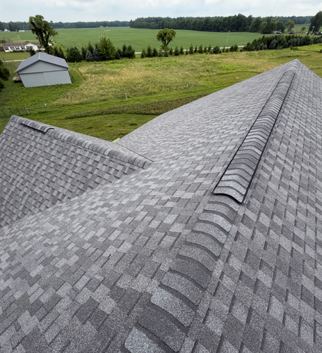 Gray shingled roof overlooking green fields and trees on a rural property
