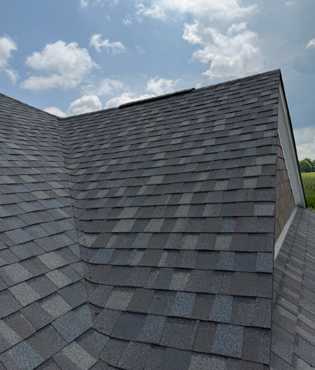 Dark gray shingled roof with a steep peak under a cloudy sky