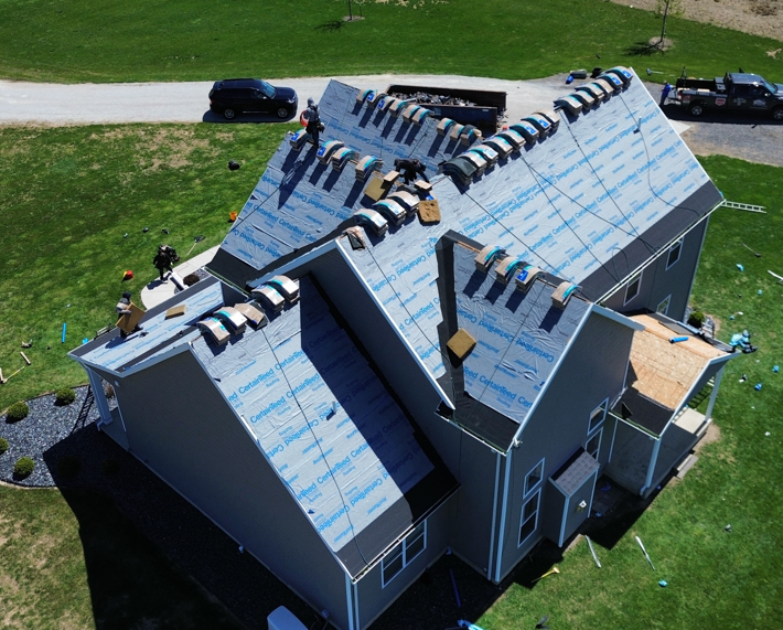 Aerial view of a gray house roof with solar panels and workers installing them