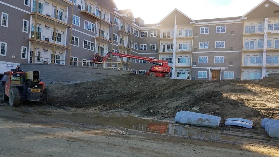 A large building under construction with a lot of dirt in front of it.