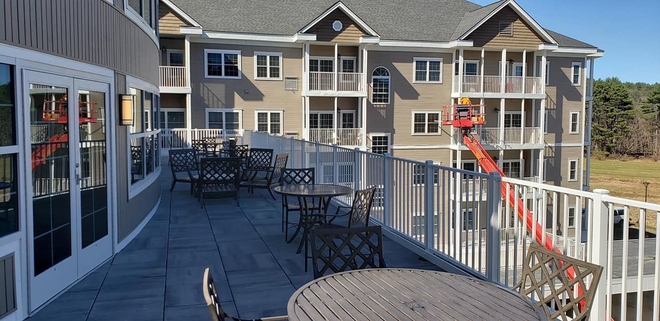 A balcony with tables and chairs in front of a large building.