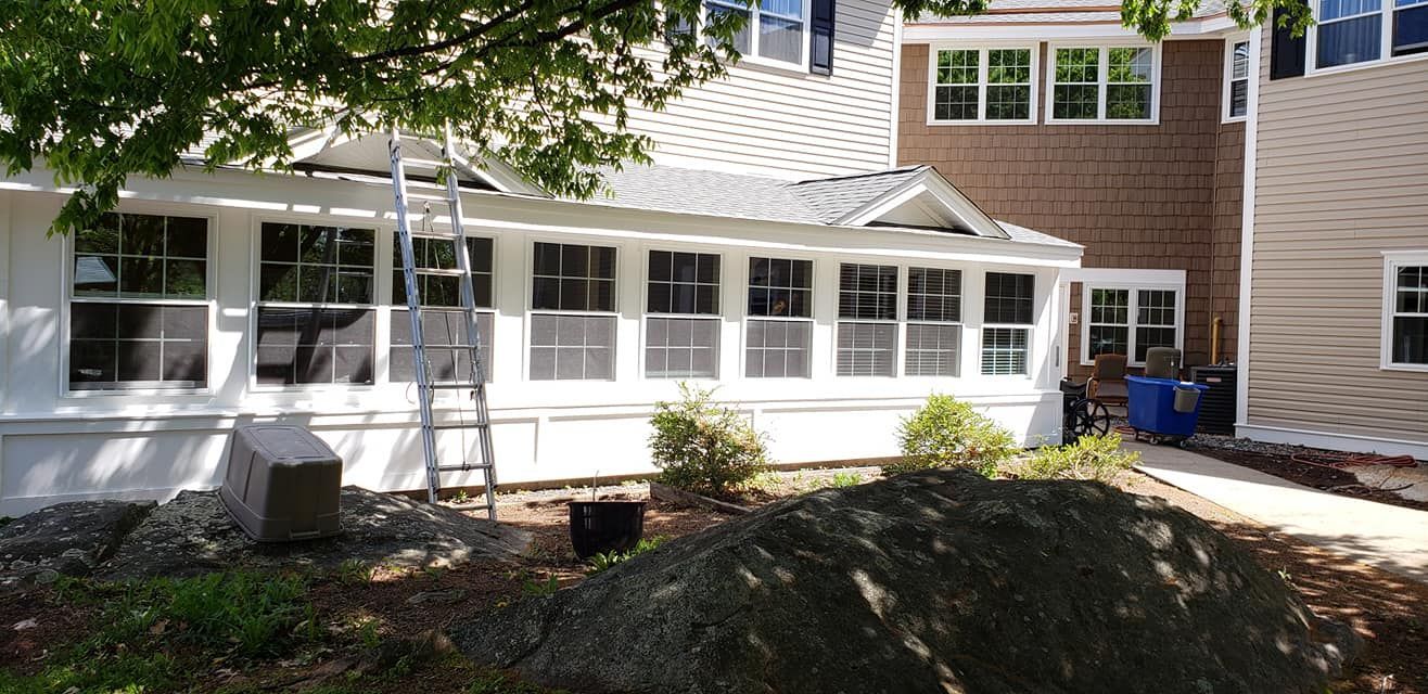 A house with a screened in porch and a ladder in front of it.