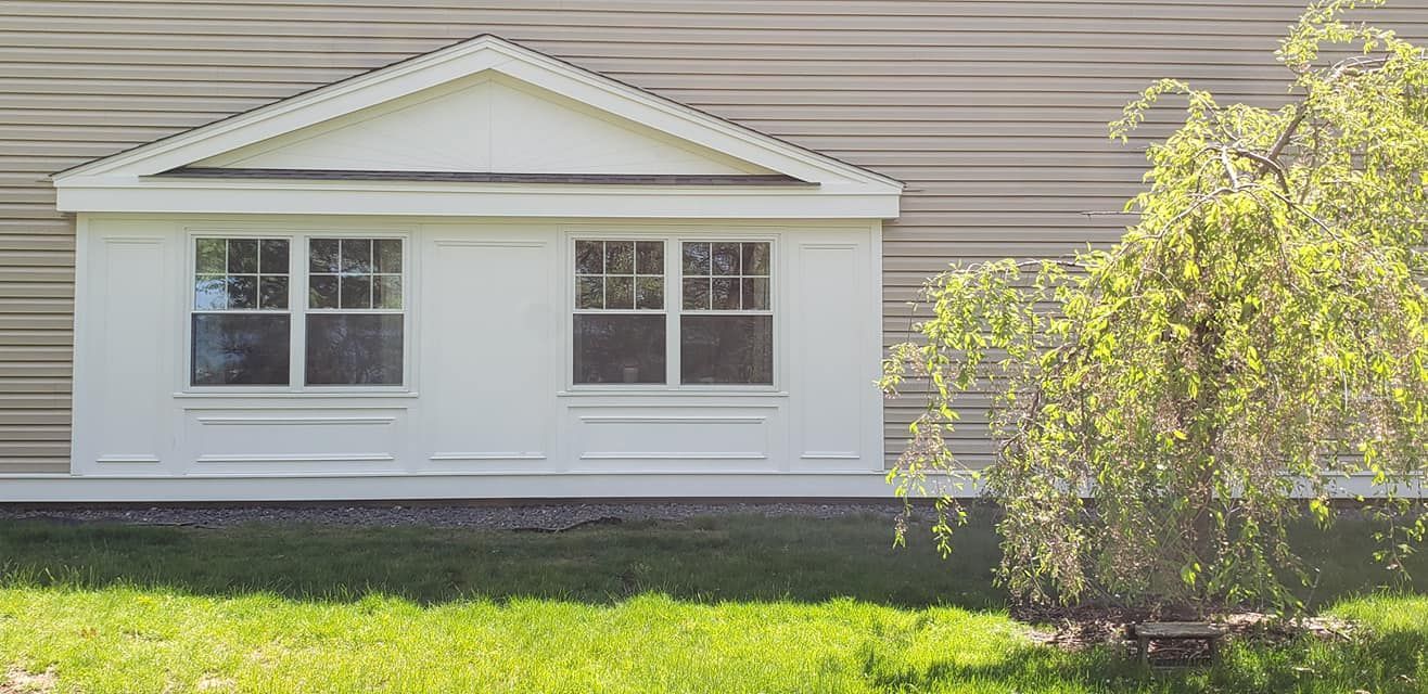 A house with a window and a tree in front of it.