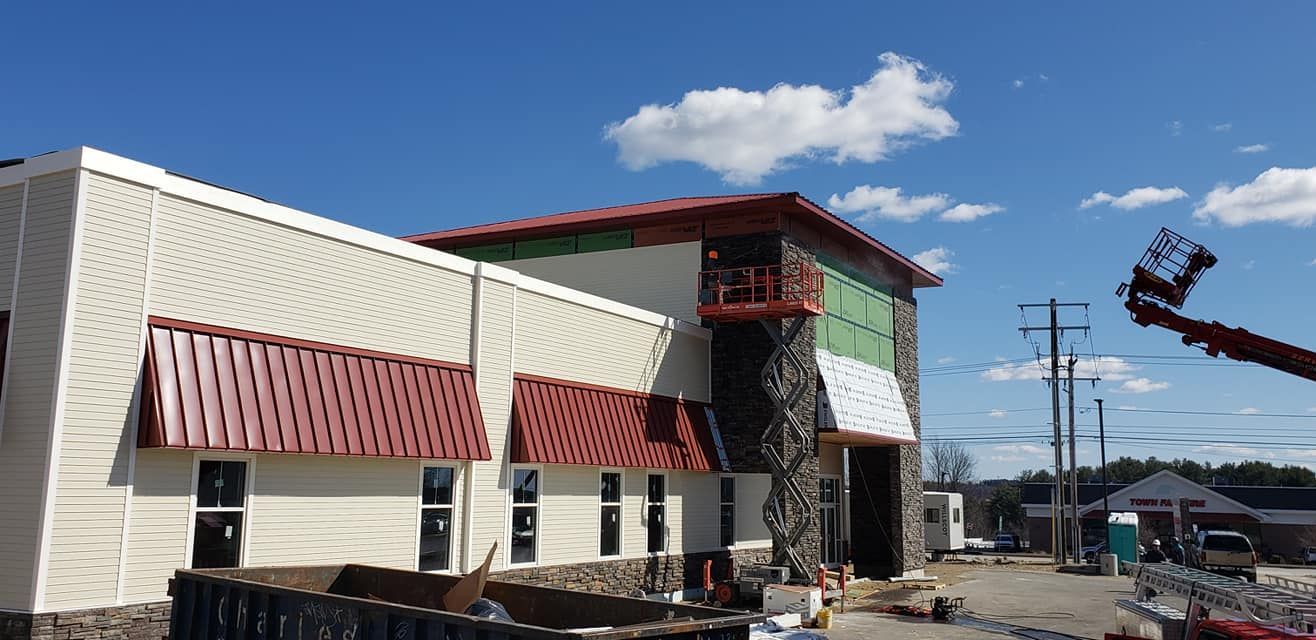 A large white building with a red awning is under construction.