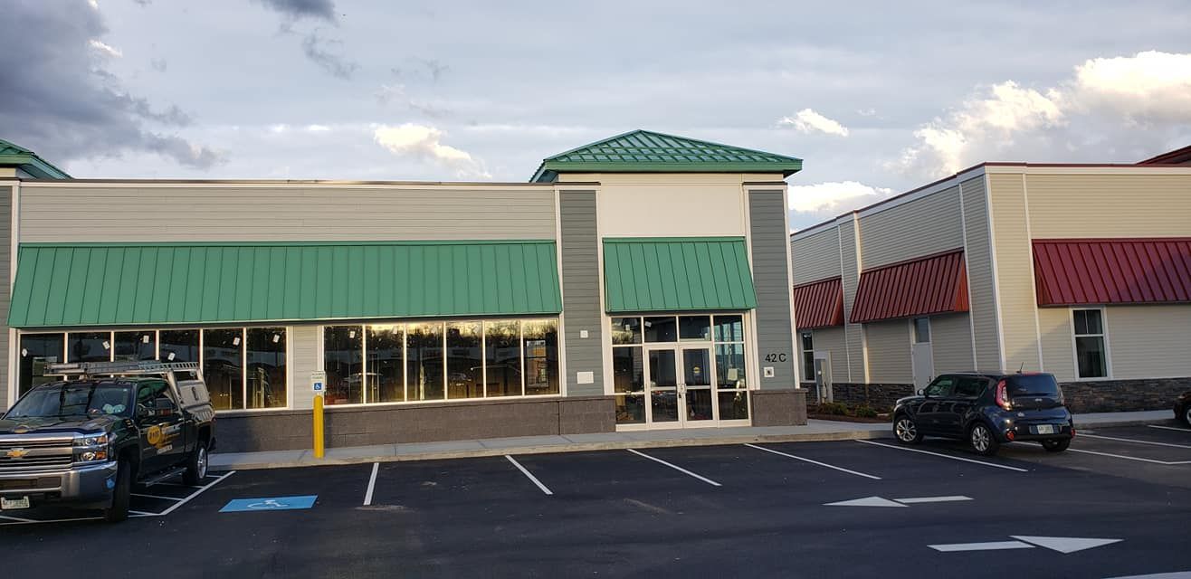 A building with a green roof and a parking lot in front of it.