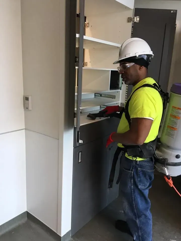 Worker in hard hat inspecting an open electrical cabinet in a hallway