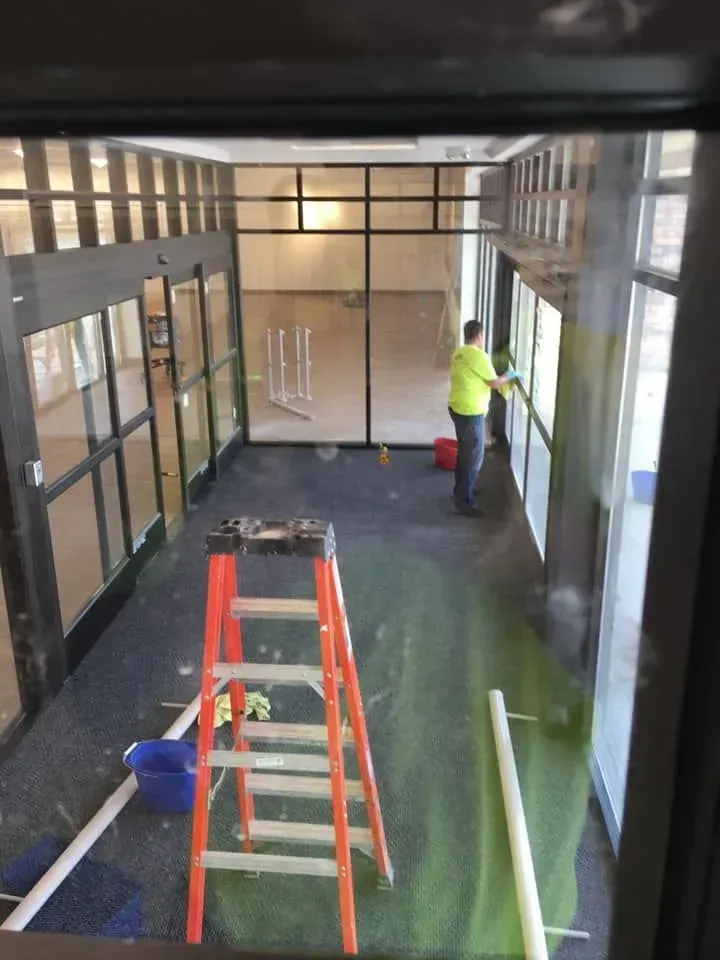 Interior renovation with ladders and a worker in a high-visibility jacket applying a window film