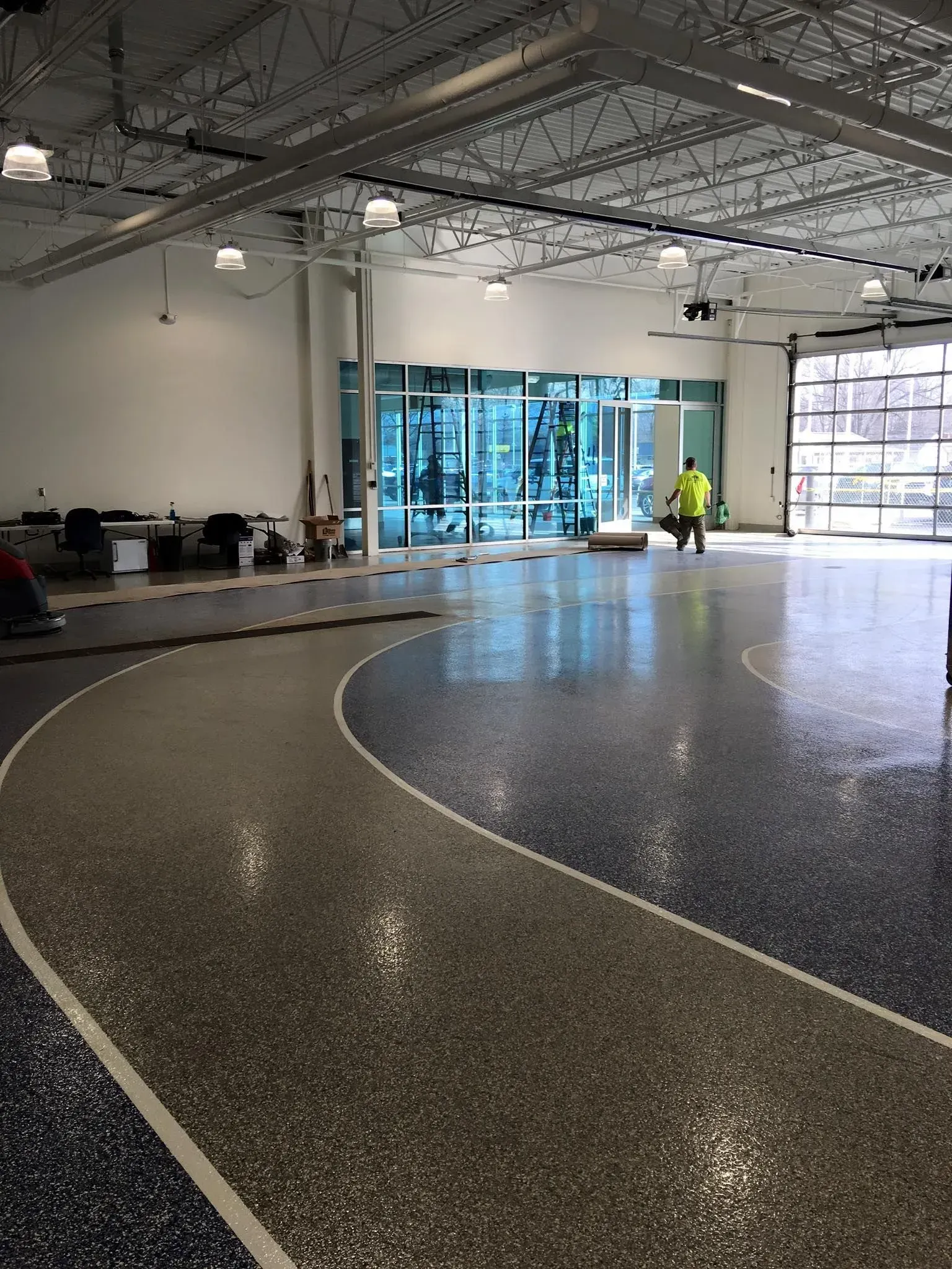 Spacious lobby with polished terrazzo floor, glass entrance, and a worker near the doors.