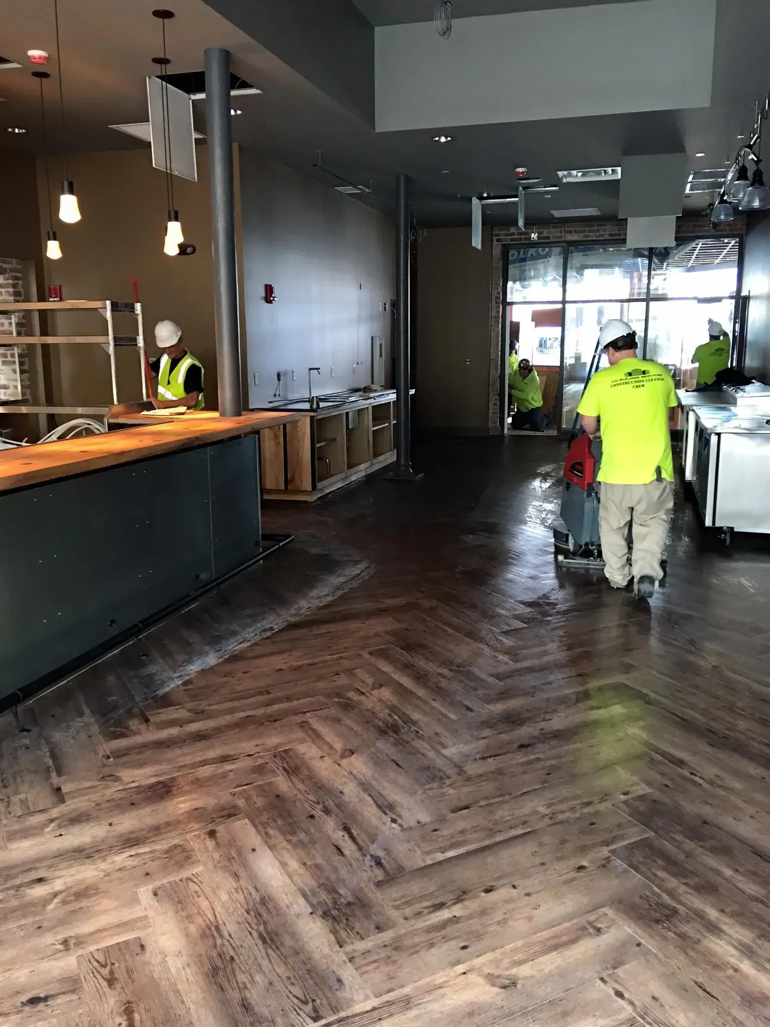 Restaurant interior with workers cleaning a dark wood floor near the entrance