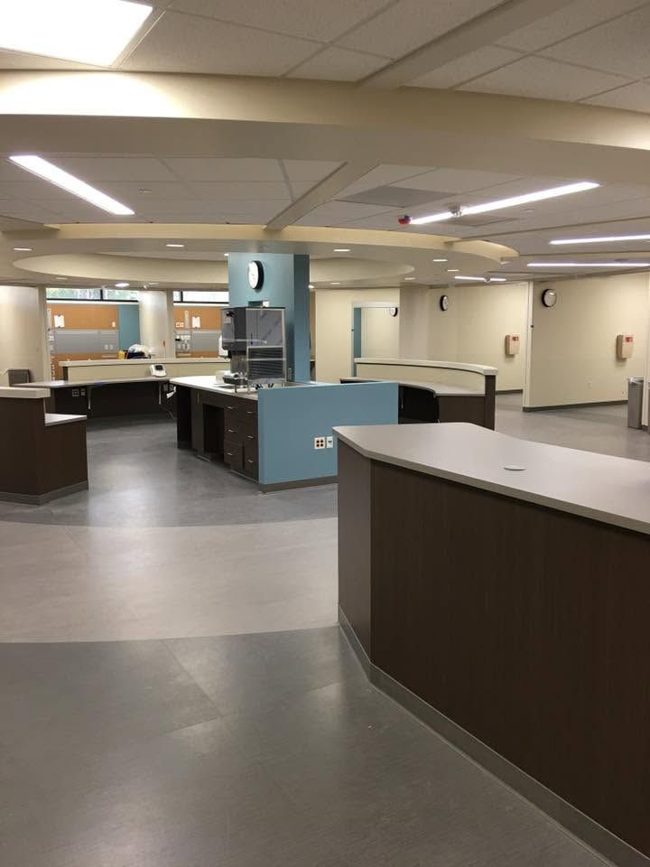 Empty hospital reception area with counters, gray flooring, and fluorescent ceiling lights