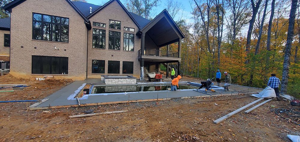 Workers install landscaping around a modern house with a patio in autumn.
